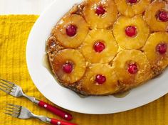 pineapple upside down cake on a white plate with red handled utensils next to it