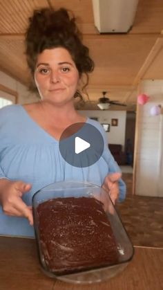 a woman holding a pan with chocolate cake in it