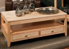 a coffee table with two drawers and a dog bowl on the bottom, in front of a brown couch