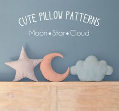 the moon, star and cloud pillows are sitting on top of a wooden shelf in front of a blue wall