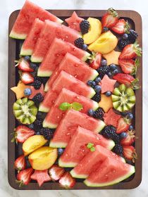 watermelon slices, kiwis, strawberries and other fruit on a cutting board