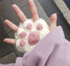 someone is holding their hand up with some crocheted flowers on it's palm