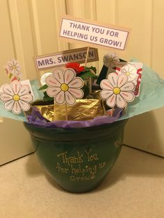 a pot filled with flowers sitting on top of a counter next to a sign that says thank you for helping us grow