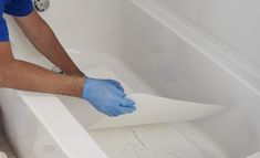 a man in blue gloves is cleaning a bathtub