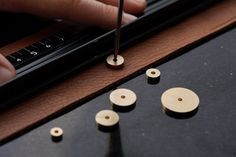 a person is working on some wooden buttons with a pen and ruler in front of them