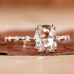 a diamond ring sitting on top of a piece of wood next to a wooden table