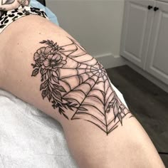 a woman's arm with a spider web tattoo on it and flowers in the center