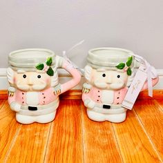 two ceramic mugs sitting on top of a wooden floor