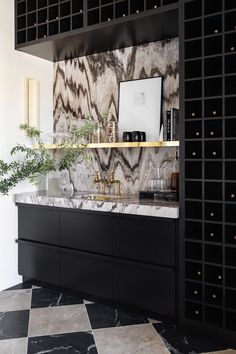 a black and white kitchen with marble counter tops, gold faucets and brass accents