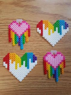 three pieces of lego art made to look like hearts and rainbows on a wooden table