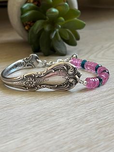 two bracelets sitting on top of a wooden table next to a potted plant