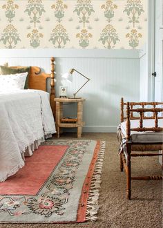 a bed sitting next to a wooden chair in a bedroom on top of a rug