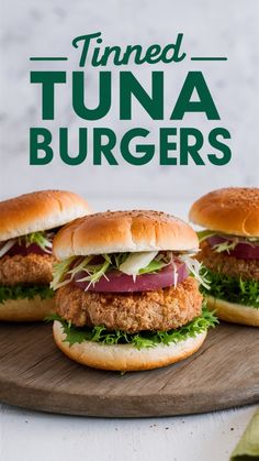 three tuna burgers with lettuce and tomato on a cutting board