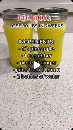 two jars filled with yellow liquid sitting on top of a counter