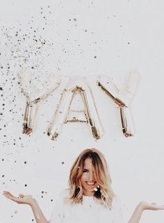 a woman standing in front of balloons that spell out the word yay with her hands