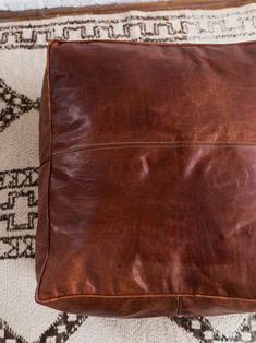 a brown leather pillow sitting on top of a rug