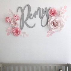 a baby's room with a crib and pink flowers on the wall above it