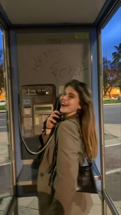 a woman talking on a phone while standing next to a parking meter