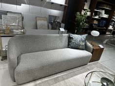 a gray couch sitting on top of a white floor next to a table and lamp