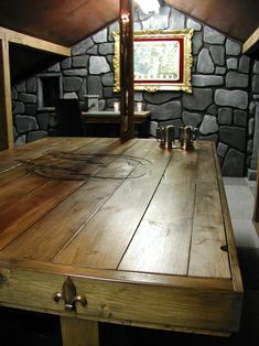 an old wooden table in the corner of a room with stone walls and wood flooring