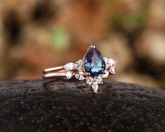 a blue and white diamond ring sitting on top of a rock