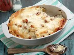 a casserole dish with meat and cheese in it on a blue table cloth