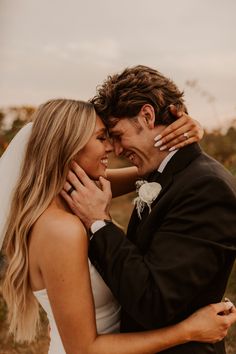 a bride and groom embracing each other outside