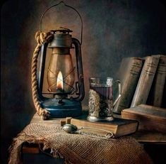 an old fashioned lantern and some books are on a table with a candle in it