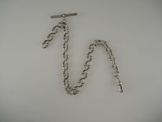 The chain is made of Continental silver; this is a lower grade of silver than English silver and so consequently it doesn't have any silver hallmarks, , just marked SS - Sterling silver. The chain measures 290mm in length from the T bar to the dog clip. This fancy watch chain is made up of oval links with ball motifs. Hanging from the T bar there is an additional length of curb links from which you could hang a fob or accessory. The chain is in 85% mint condition - the ends of the links are worn Victorian Silver Chain Jewelry, Silver Oval Link Curb Chain Bracelet, Silver Curb Chain Bracelet With Oval Link, Silver Hallmarked Oval Link Chain Necklace, Silver Oval Link Chain Necklace Hallmarked, Silver Double Chain Link Bracelet, Antique Silver Chain Necklace, Silver Engraved Chain Necklace For Formal Occasions, Victorian Silver Curb Chain Jewelry