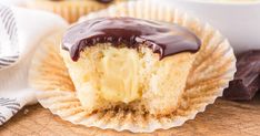 a chocolate covered cupcake sitting on top of a wooden cutting board