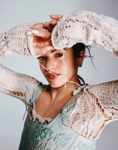 a woman is holding her hands to her head while posing for the camera with lace on it