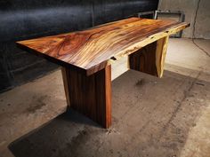 a wooden table sitting on top of a floor next to a black wall in a room