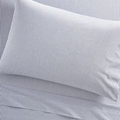 a close up of a bed with blue and white striped sheets on top of it