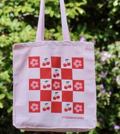 Pack up a picnic in this vibrant pink tote bag, displaying a checkerboard of cherries and cherry blossoms. It's the perfect accessory for spring! Summer Cotton Bag For Picnic, Cotton Summer Picnic Bag, Cotton Picnic Bag For Summer, Red Spring Picnic Bag, Spring Picnic Cotton Bag, Retro Pink Bags For Spring, Summer Gingham Cotton Bags, Gingham Cotton Bags For Summer, Retro Pink Cotton Bag