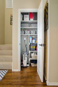 an open door leading to a closet with shelves and baskets on the bottom shelf in front of stairs