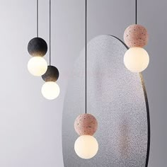 three different colored lights hanging from the ceiling in front of a mirror and circular light fixture