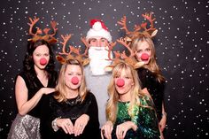 a group of people standing next to each other in front of a christmas photo booth