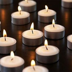 many white candles are lit on a black surface