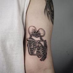 a man with a tattoo on his arm holding a skeleton in the shape of a heart