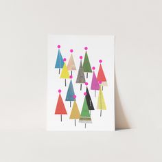 a card with colorful trees on it sitting next to a white wall in the background