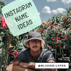 a man with his arms crossed sitting in front of some plants and flowers, holding a sign that says instagram name ideas