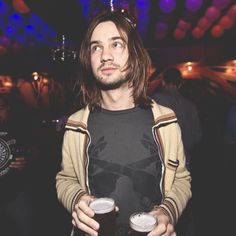 a man with long hair holding two beer glasses