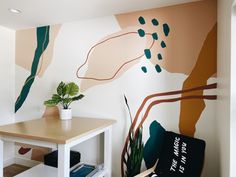 a white table with a plant on it next to a painted wall in a room