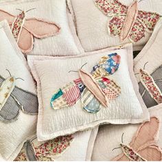 several pillows with different designs on them and one has a butterfly appliqued on it