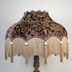 a lamp that has fringes on it and is next to a wall with a white background