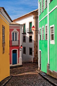 an alley way with colorful buildings and cobblestone pavement in the foreground on a sunny day