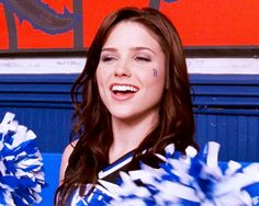 a cheerleader with blue and white pom poms