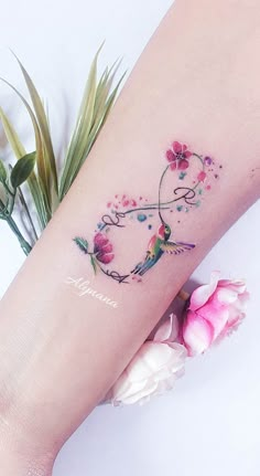 a woman's arm with a tattoo on it and pink flowers in the background