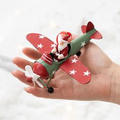 a hand holding a toy airplane with santa clause on it