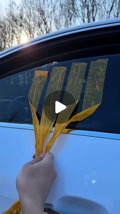 someone is holding up some yellow flowers in front of a car